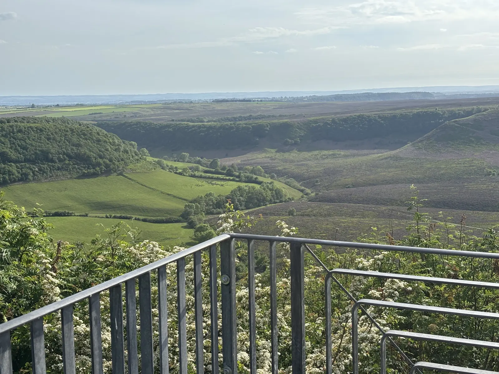 Panoramic view across a green valley and the heather moors of the Yorkshire coast from a countryside viewpoint